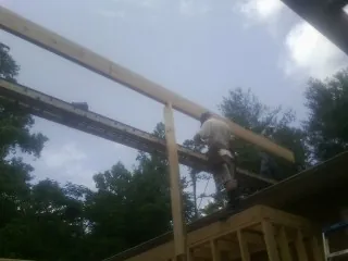Carpenter setting a ridge beam over a new addition frame — Ice Dam Removal by Roofing Brothers in Stennis Space Center