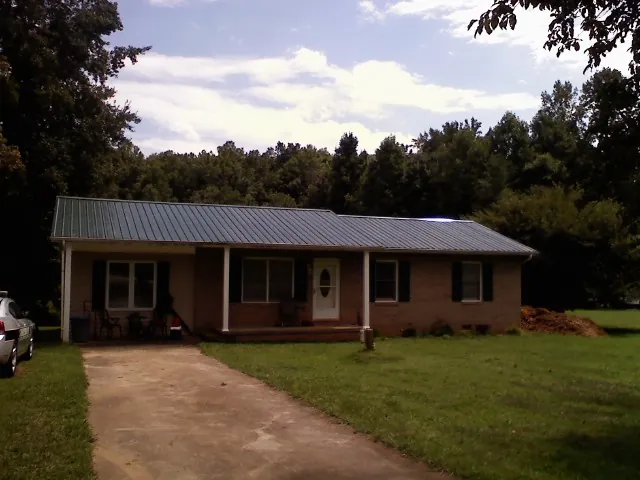 Dark green metal roof on a brick ranch with a covered porch in Stennis Space Center