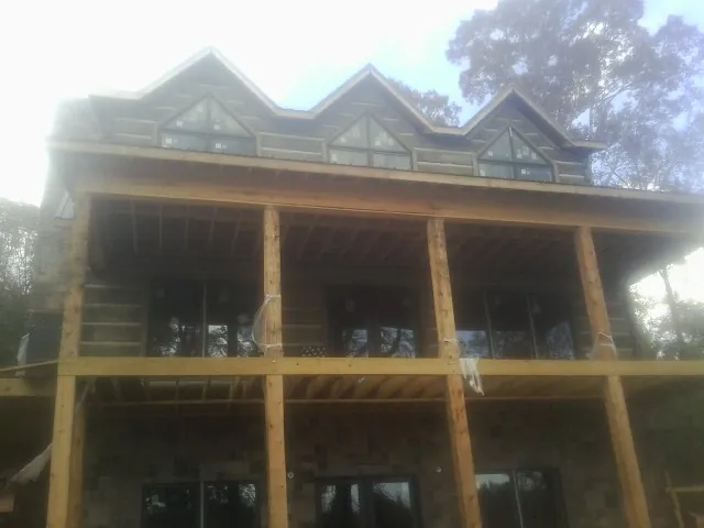 Dormers and porch framing on a large log home under construction — Roof Coating work by our crew in Stennis Space Center