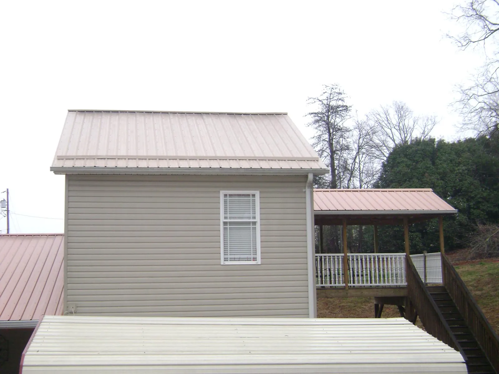Tan metal roofs on a two story addition and attached porch, from a Roof Replacement job in Stennis Space Center